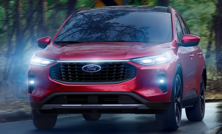 vehicle parked on the beach, with a woman bringing her surfboard to the rear